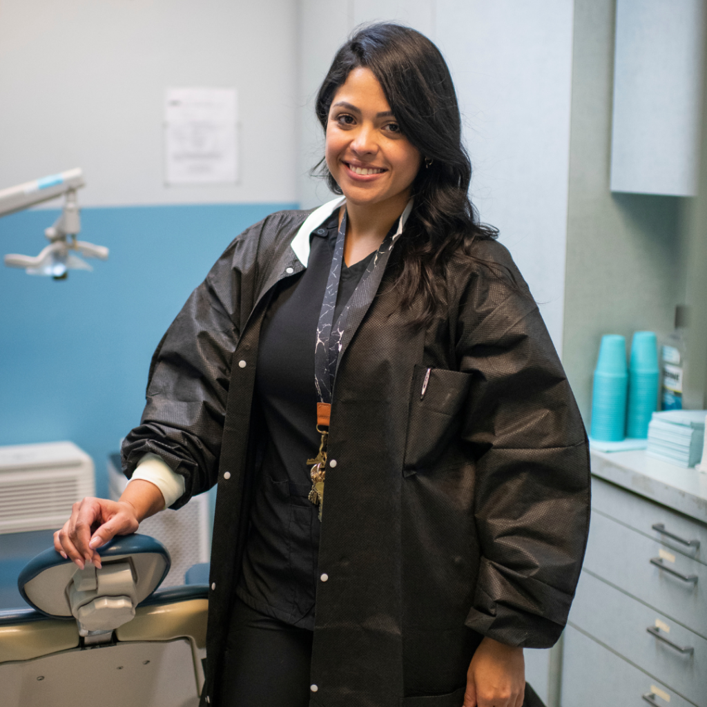 A Project Renewal dental hygienist stands in one of the Fort Washington Dental Clinic examination rooms, smiling brightly!